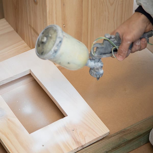 man painting with paint gun furniture, child's kitchen, homemade